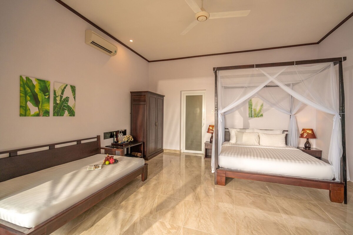 Une chambre à coucher comprenant un lit, une table de chevet, une lampe, une armoire et un ventilateur de plafond.
