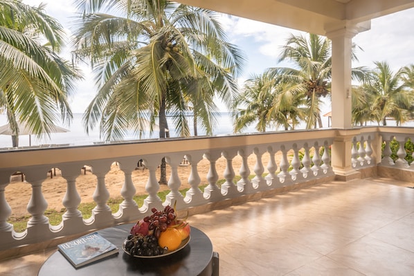 A balcony with a view of the beach and palm trees.