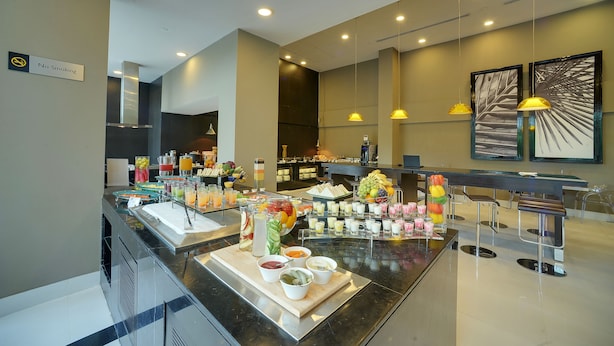 A buffet area with various food and drink options, a no-smoking sign, and modern lighting fixtures.