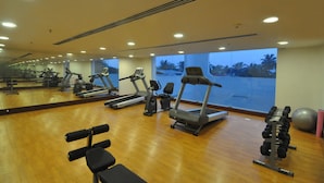 A gym with exercise equipment, a large mirror, and a view of palm trees.