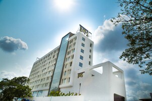 Un hotel moderno con un llamativo letrero que dice 'HOTEL', fachada de vidrio y exterior blanco.