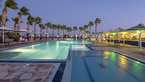A swimming pool with a 'No Diving' sign, surrounded by palm trees and lounge chairs, with a view of the ocean at dusk. - Mammis Beach (Kos)