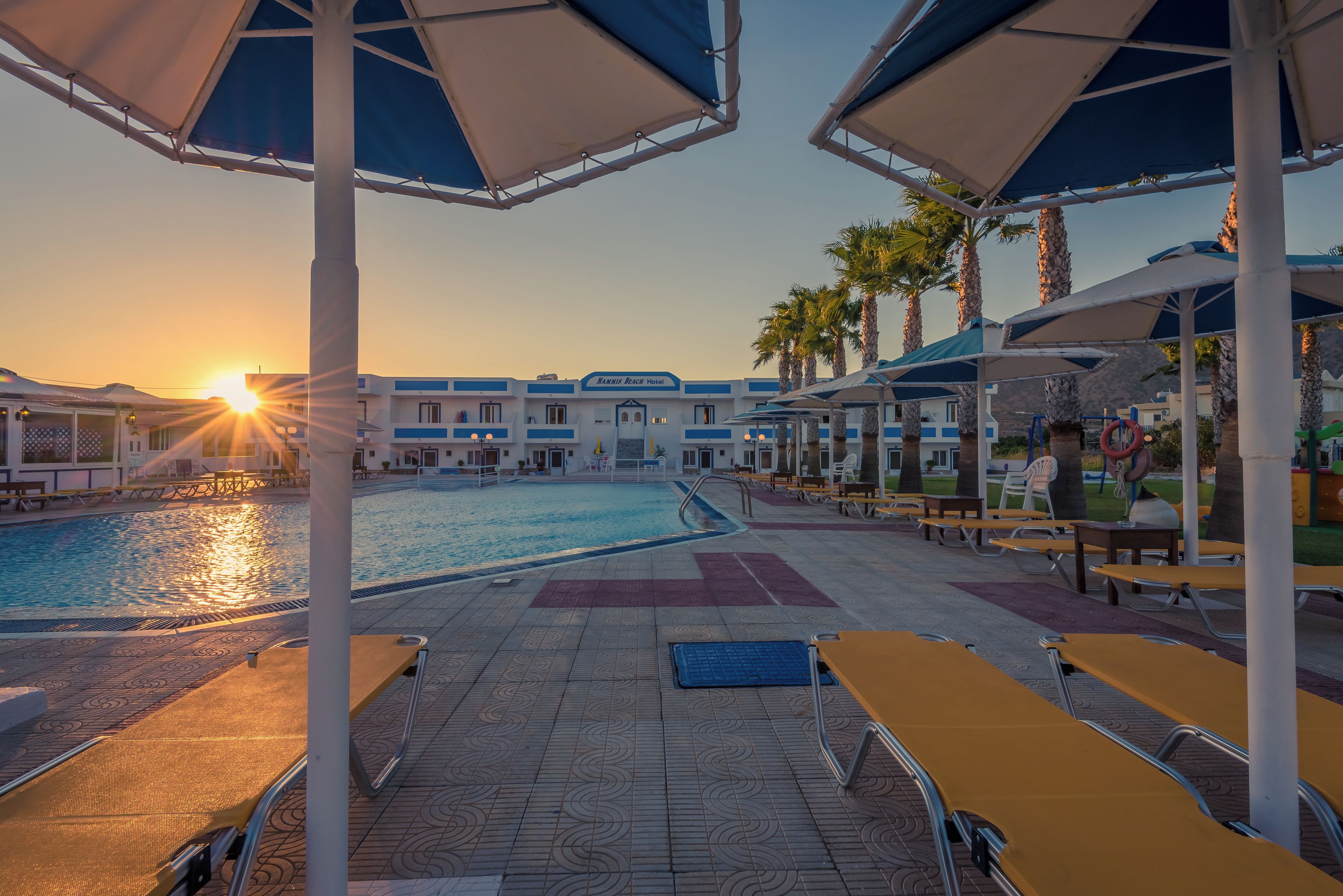 A poolside area with umbrellas, lounge chairs, and a pool.