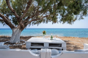 Ein Tisch im Freien mit Blick auf das Meer, einen Baum und eine Holztischplatte.