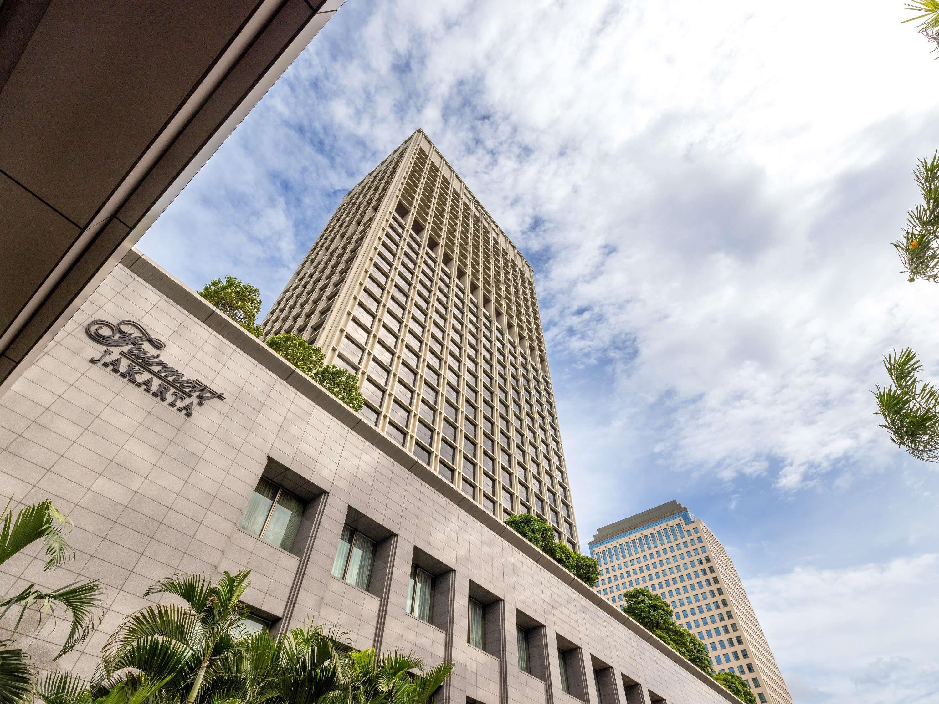 Un edificio alto con una facciata a griglia e un cartello con la scritta "Fairmont Jakarta".