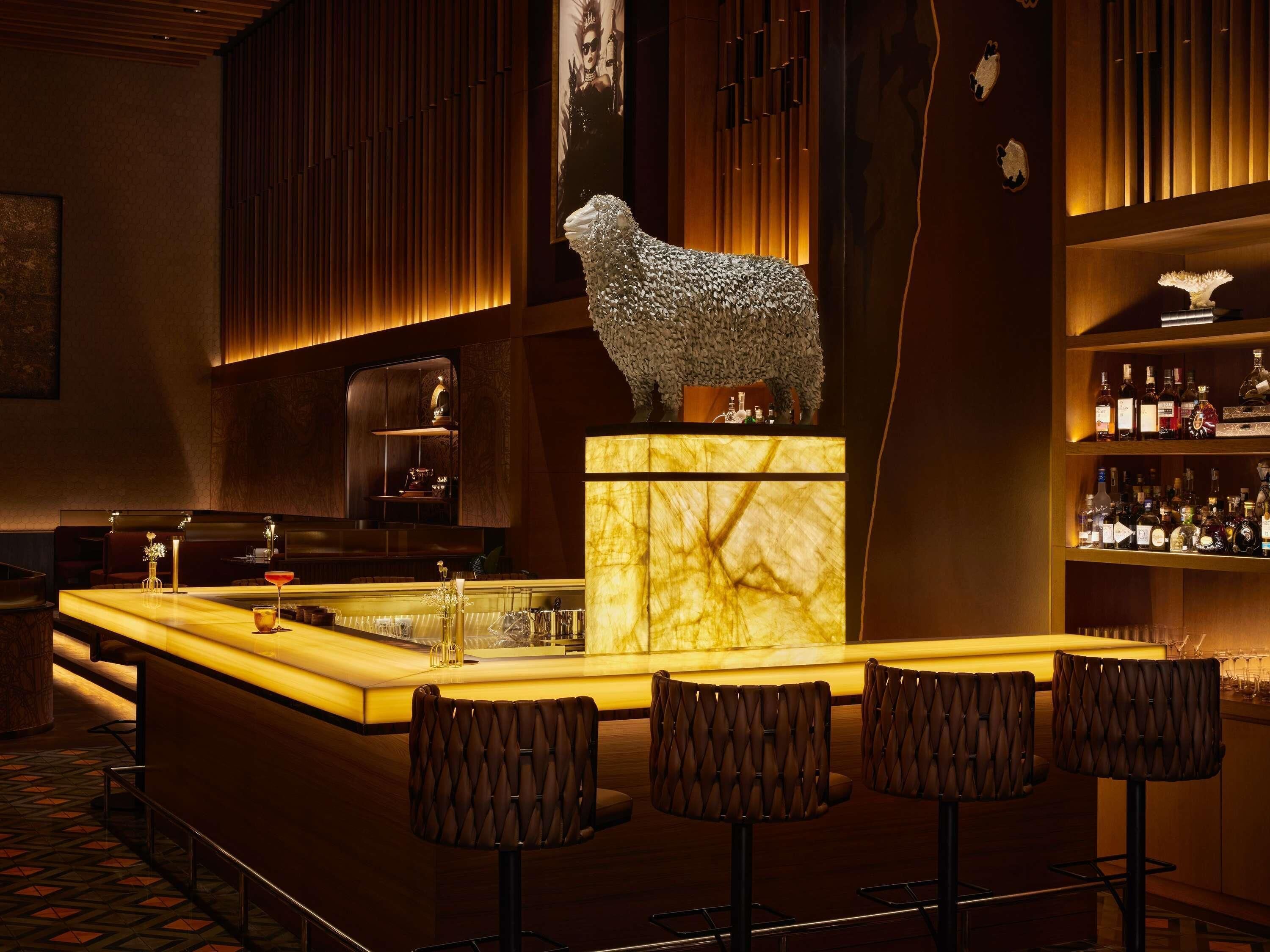 A bar area with a marble counter, bar stools, and a decorative sculpture.