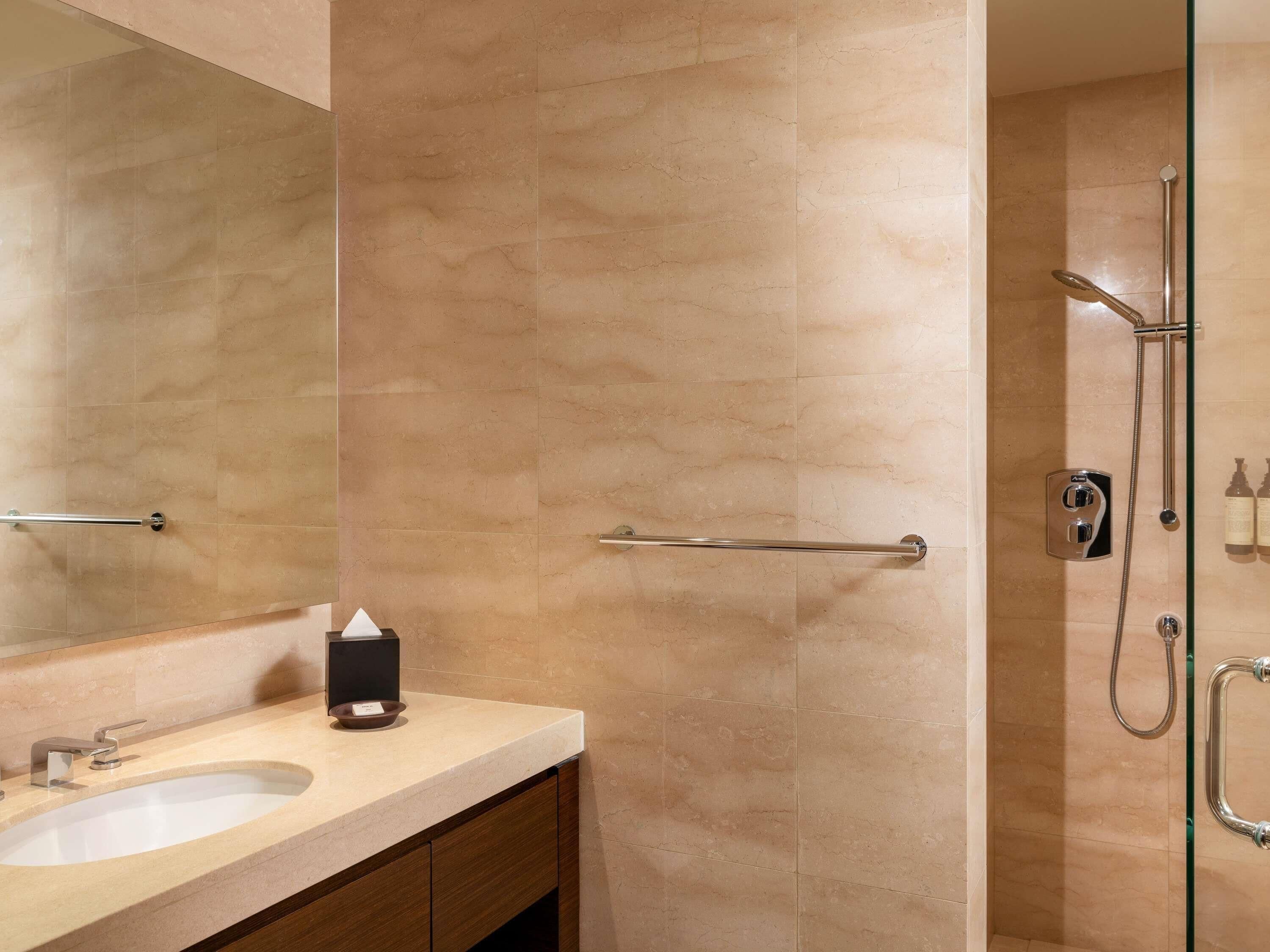 A bathroom with a sink, mirror, towel rack, and shower with a handheld showerhead.