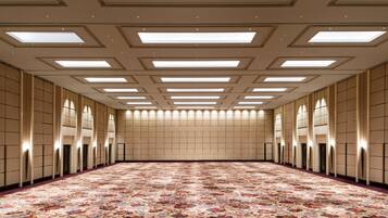 A large, well-lit room with a patterned carpet, recessed lighting, and a high ceiling with skylights.
