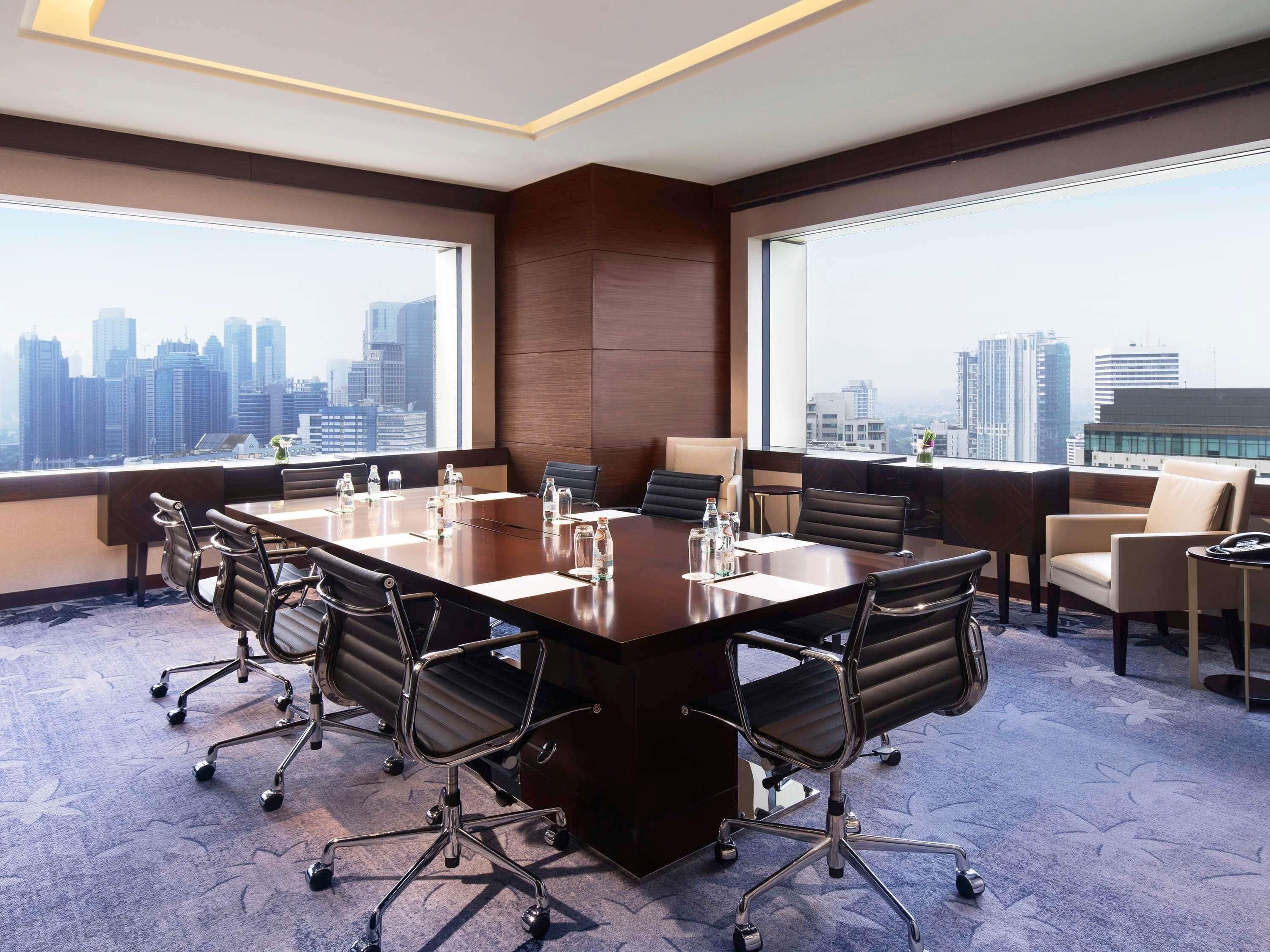 Un salón de conferencias con una amplia mesa, sillas y vistas a la ciudad.