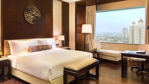 Habitación de hotel con una cama grande, un escritorio, una silla y vistas a la ciudad.