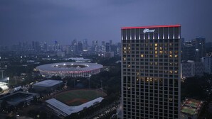 Un rascacielos con un llamativo letrero de 'Fairmont', rodeado de un paisaje urbano con diversos edificios y un estadio.
