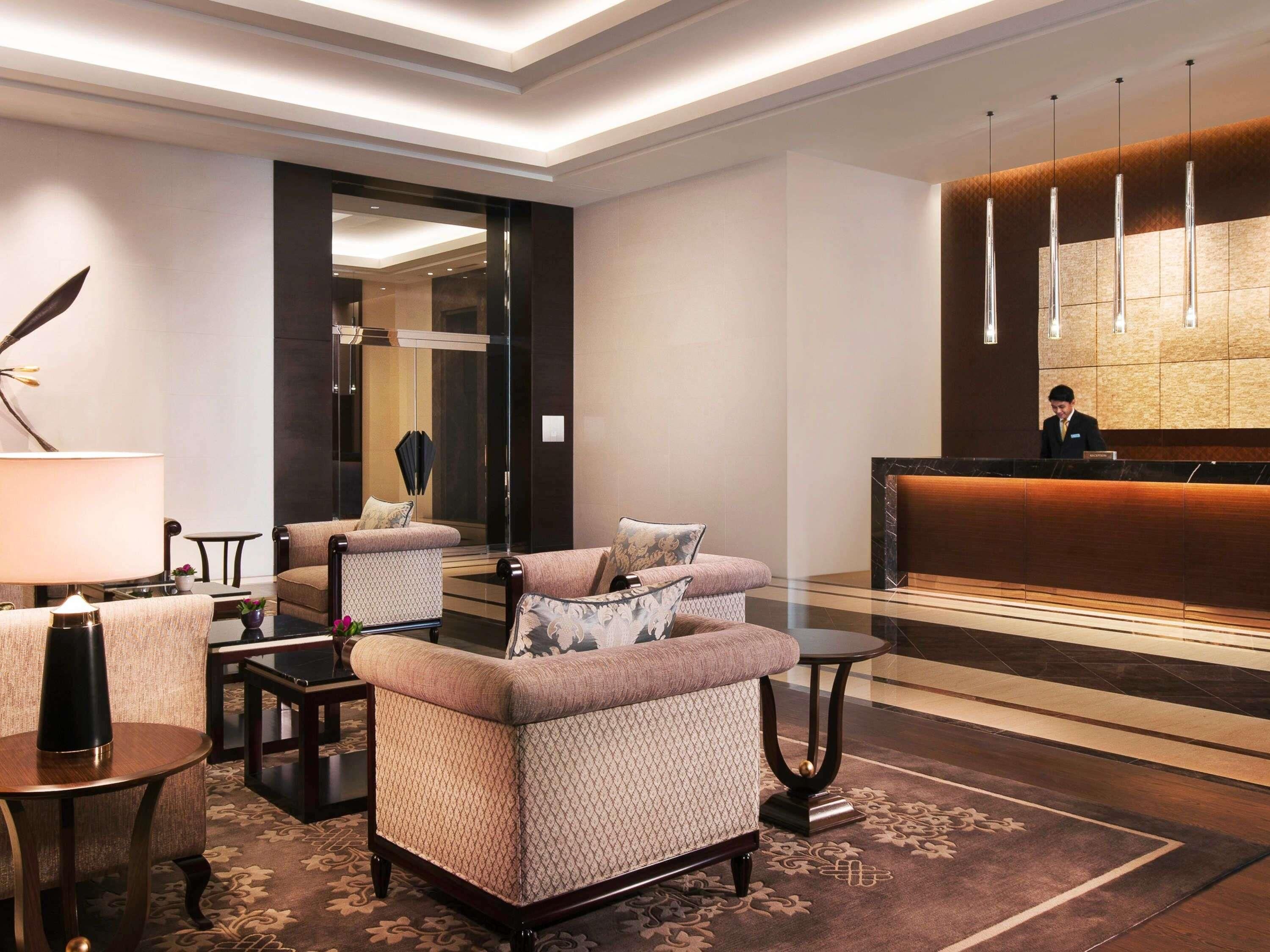 A lobby with sofas, a reception desk, and a mirror.