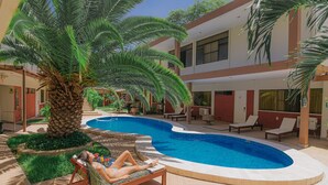 A pool area with a lounge chair and a palm tree. - El Angolo Hotel Piura (Piura)