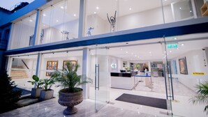 A modern hotel lobby with a reception desk, glass doors, and potted plants. - El Angolo Hotel Piura (Piura)
