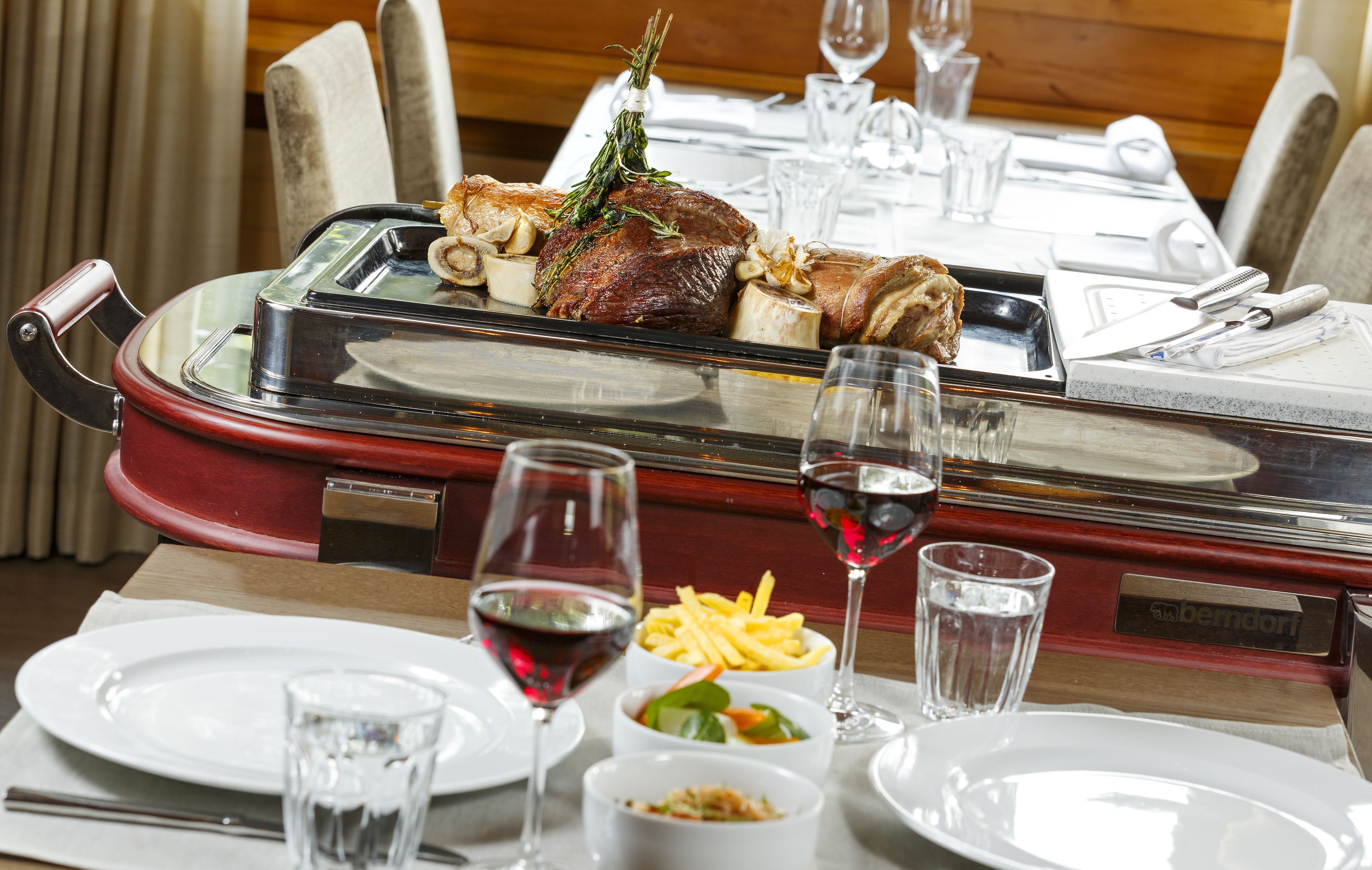 A dining table set with plates, glasses, and a glass of red wine.