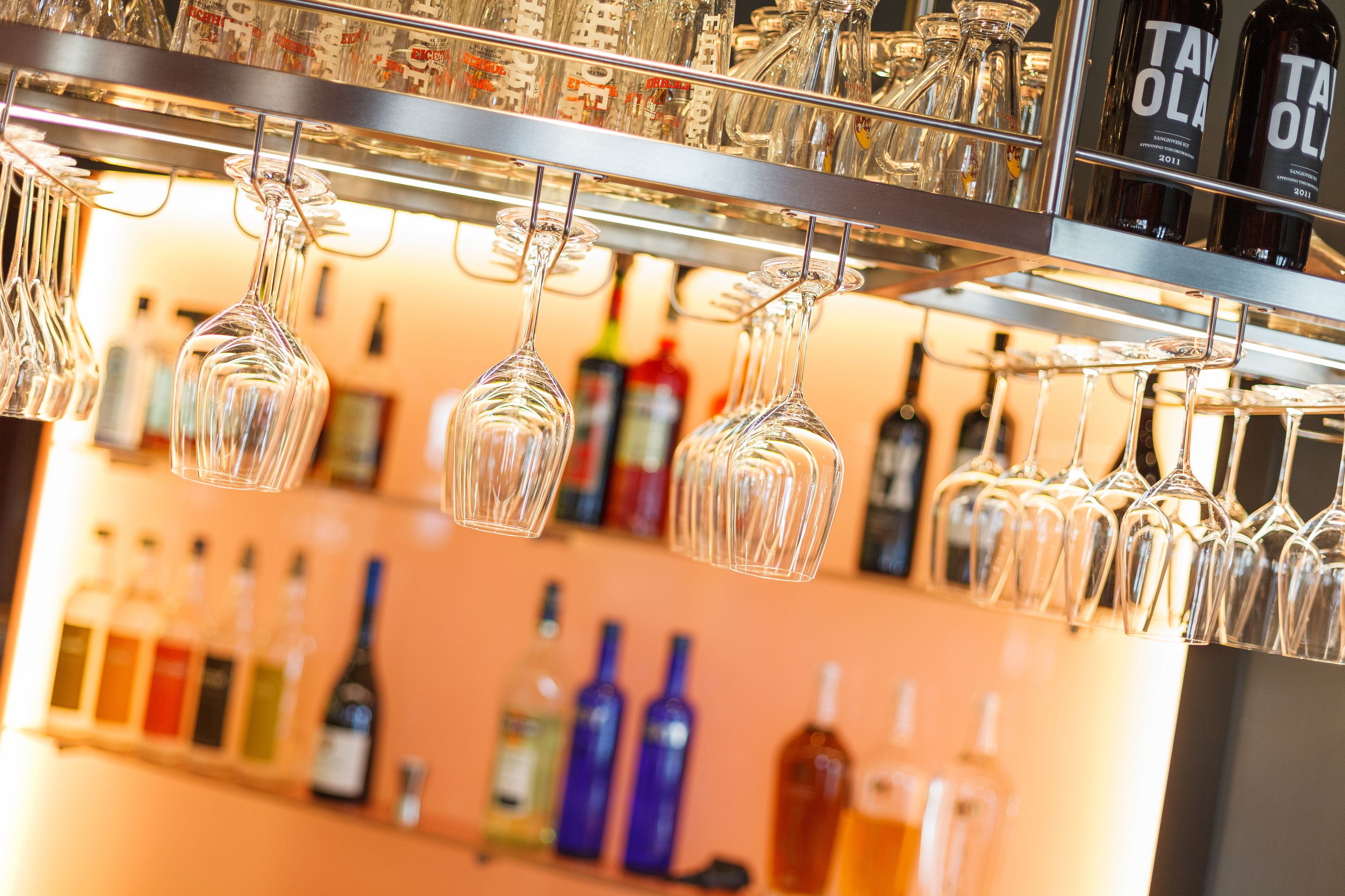 A bar area with hanging wine glasses and a variety of liquor bottles on shelves.