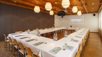 Une salle de conférence avec de longues tables, des chaises et des luminaires suspendus.