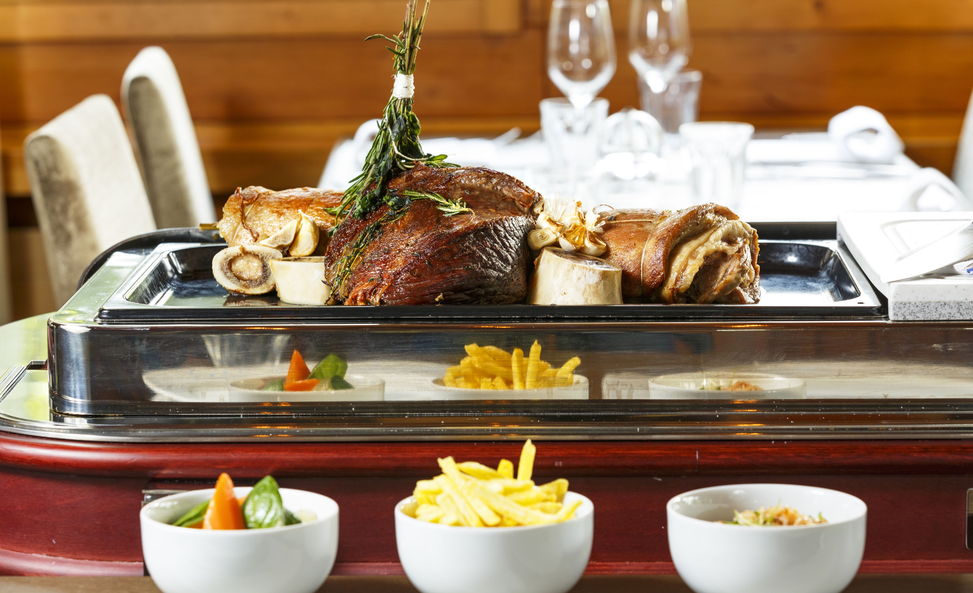 A dining table with a roasted duck, garlic, and herbs. There are three small bowls with different food items.