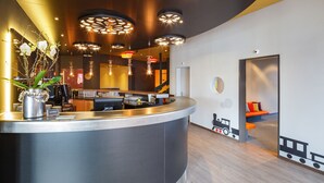 A modern reception area with a curved counter, a vase of white flowers, and a train-themed wall decoration. - CHÄRNSMATT Gasthof & Spielparadies (Rothenburg)