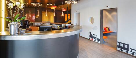 A modern reception area with a curved counter, a vase of white flowers, and a train-themed wall decoration.