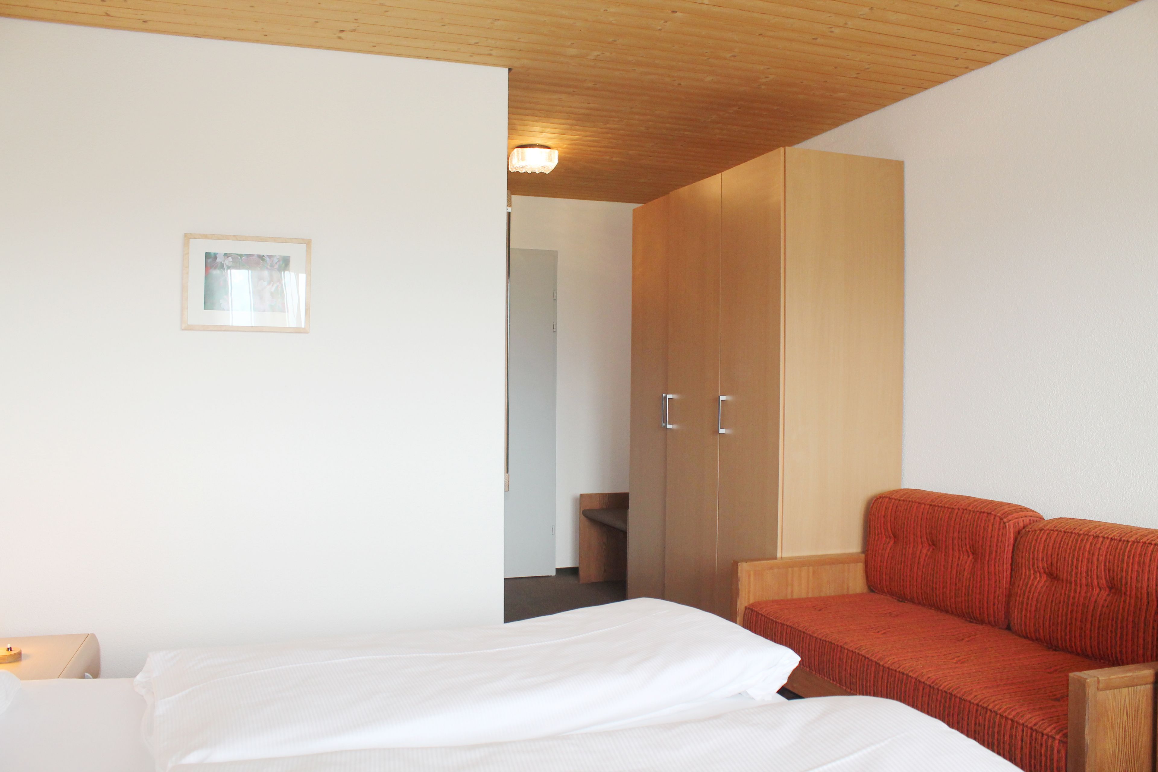 Une chambre à coucher avec un lit, un canapé rouge et une armoire.