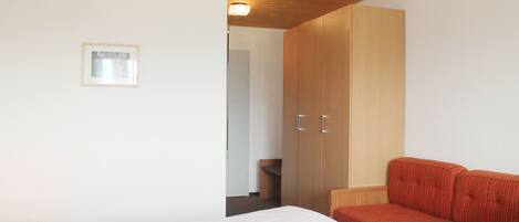 Une chambre à coucher avec un lit, un canapé rouge et une armoire.