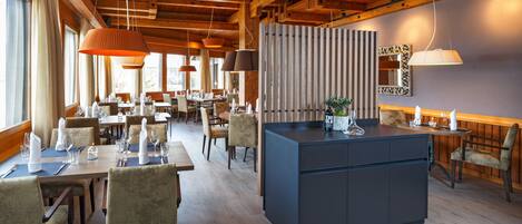 A spacious dining area with wooden beams, multiple tables, and chairs.