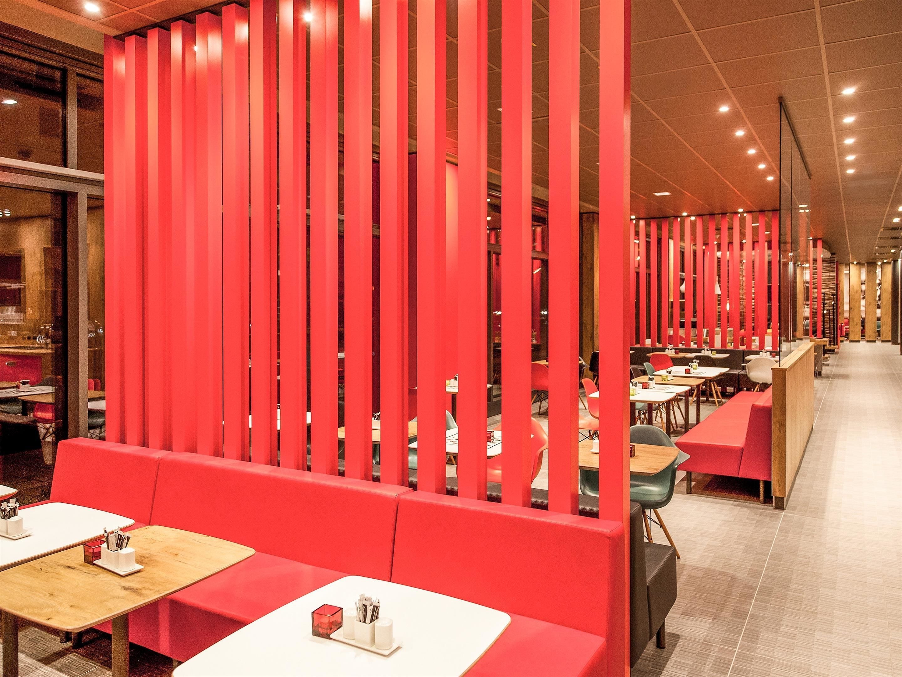 A modern restaurant with red seating and wooden tables.