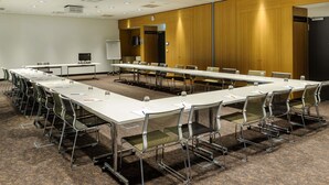 A conference room with long tables, chairs, a whiteboard, and a clock on the wall. - Ibis Muenchen City Arnulfpark (Munich)