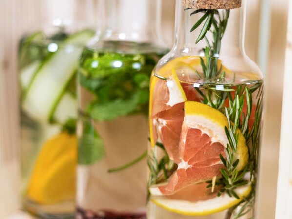 Una botella con corcho, con rodajas de limón, romero y un trozo de carne.