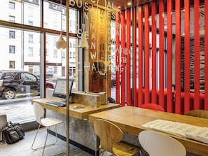 A modern workspace with a wooden desk, a laptop, and a chair. - Ibis Muenchen City Arnulfpark (Munich)