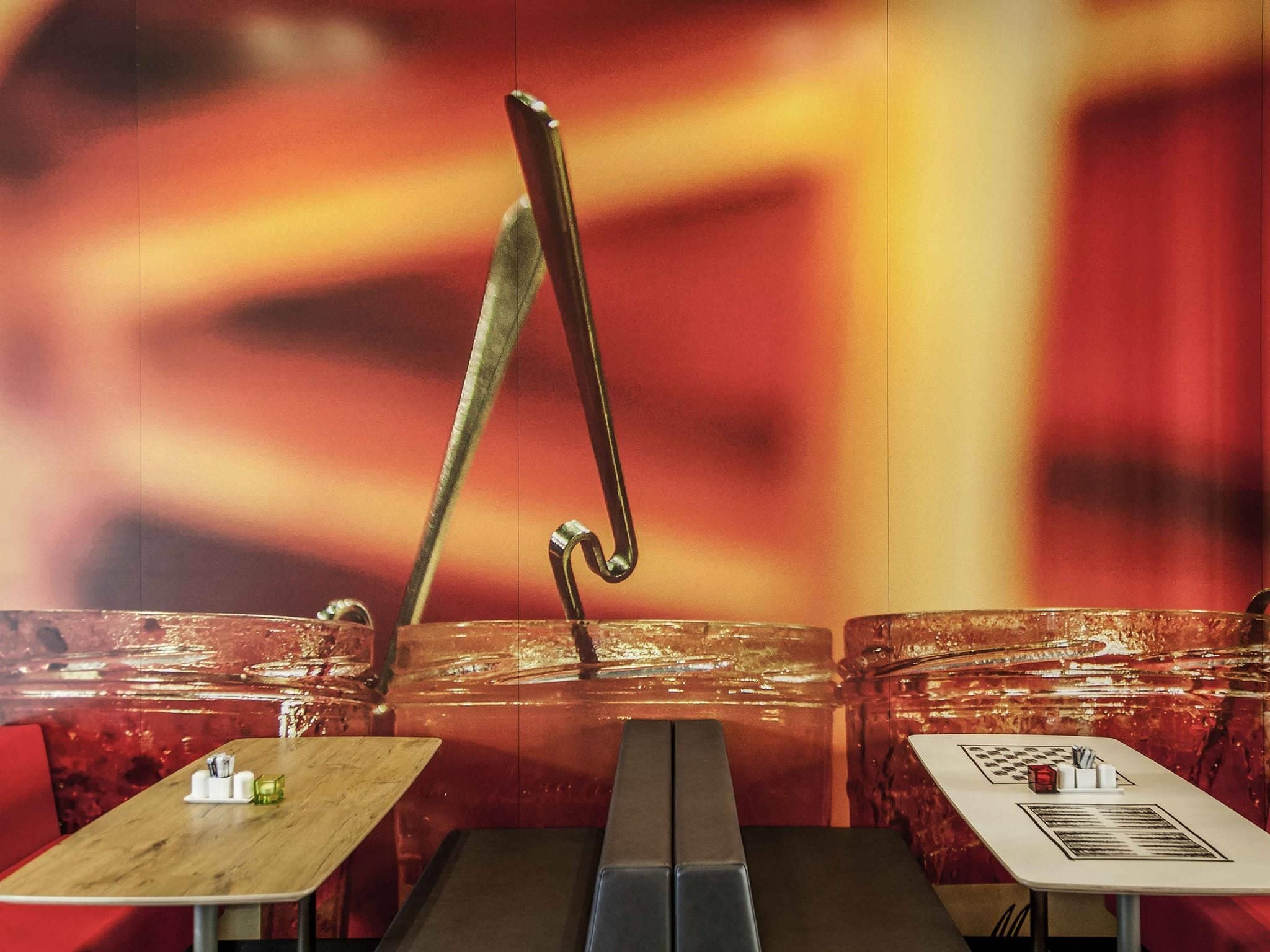 A restaurant with a modern interior, featuring a central table with a unique metal sculpture, and two smaller tables with menus.