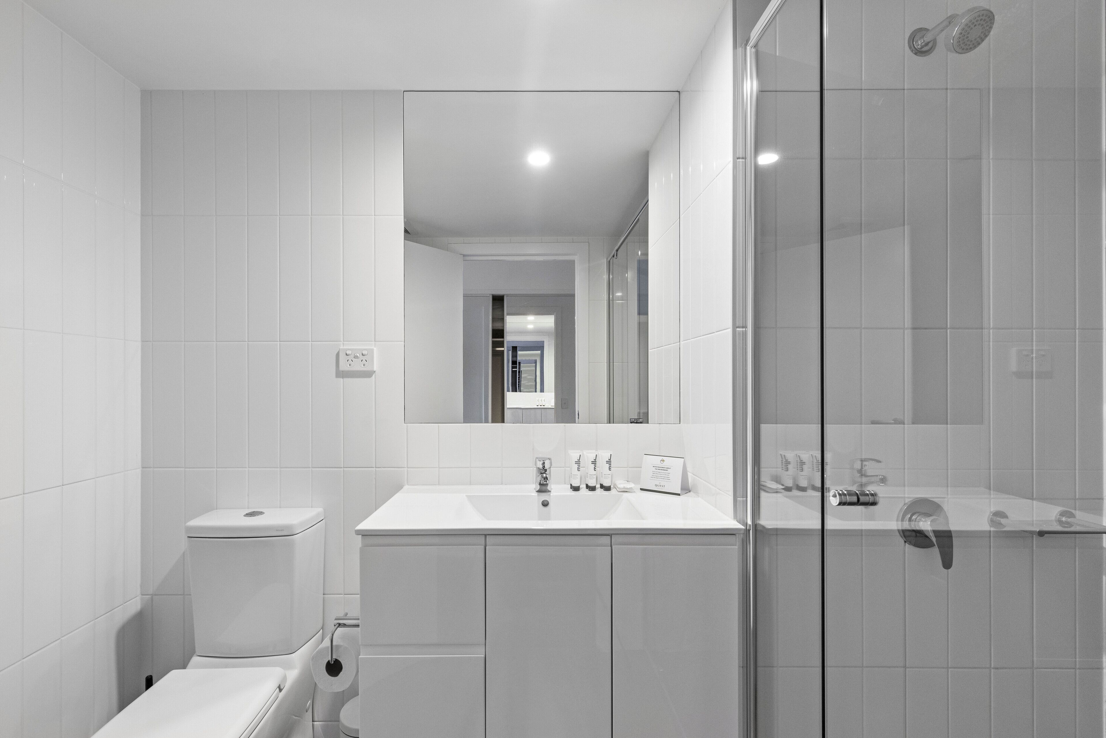 A modern bathroom with a toilet, sink, and shower.