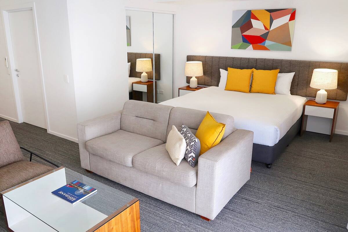 Una habitación de hotel con una cama, un sofá, una mesa de centro y un espejo.