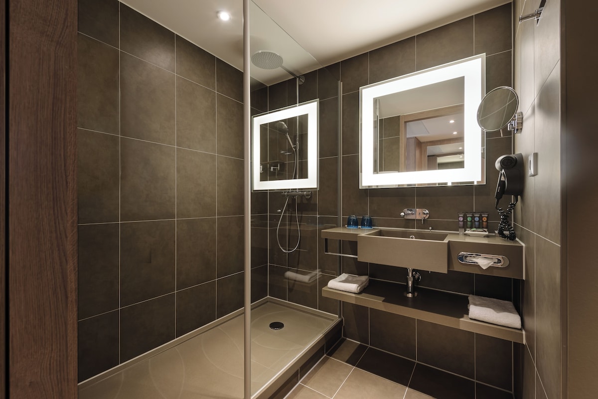 A modern bathroom with a glass-enclosed shower, a vanity with a mirror, and a towel rack.
