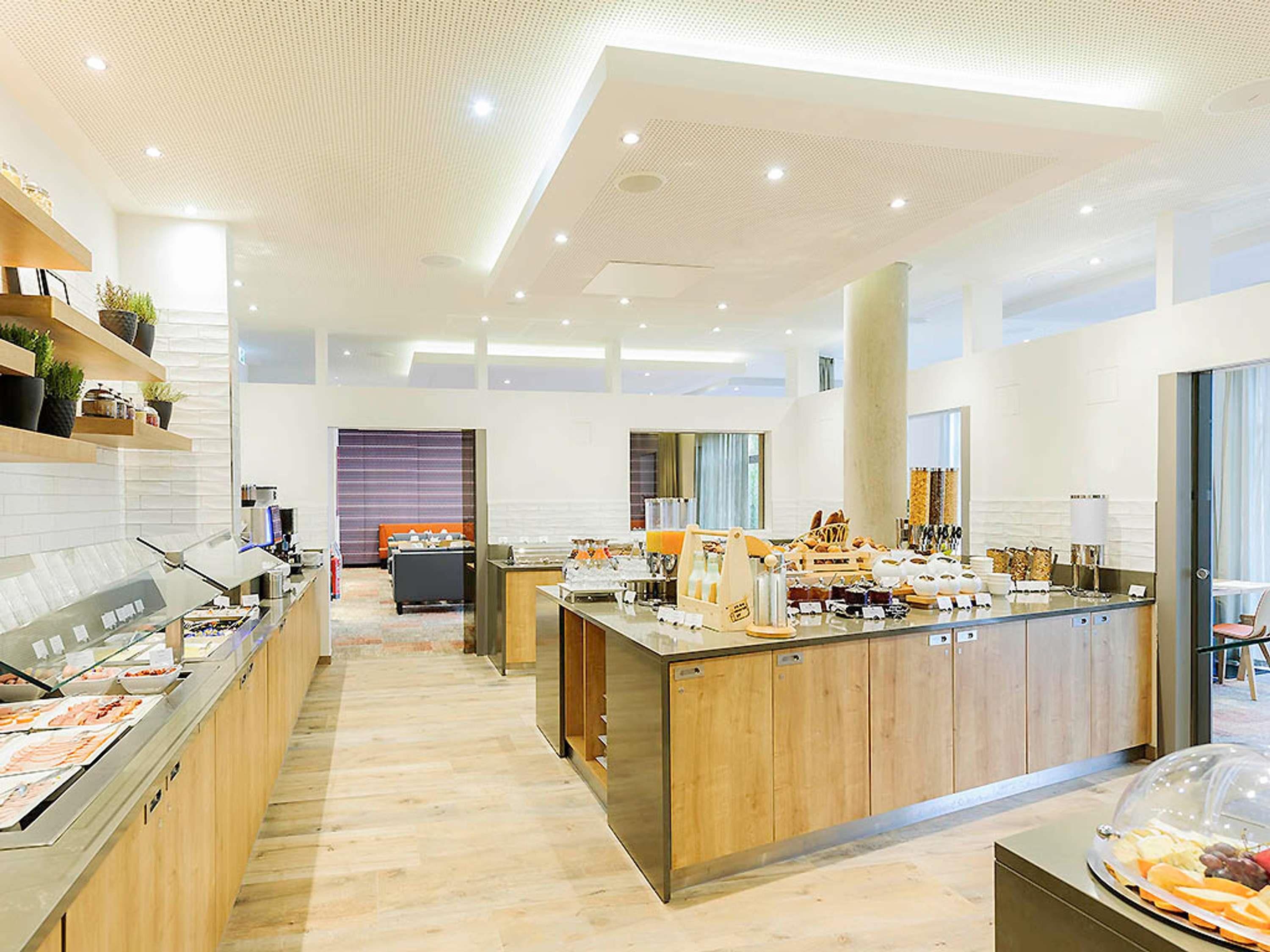A modern hotel lobby with a central reception desk, a seating area with a sofa, and a buffet counter with various food items.