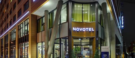 Un hotel Novotel con fachada moderna, grandes ventanales y una entrada destacada.