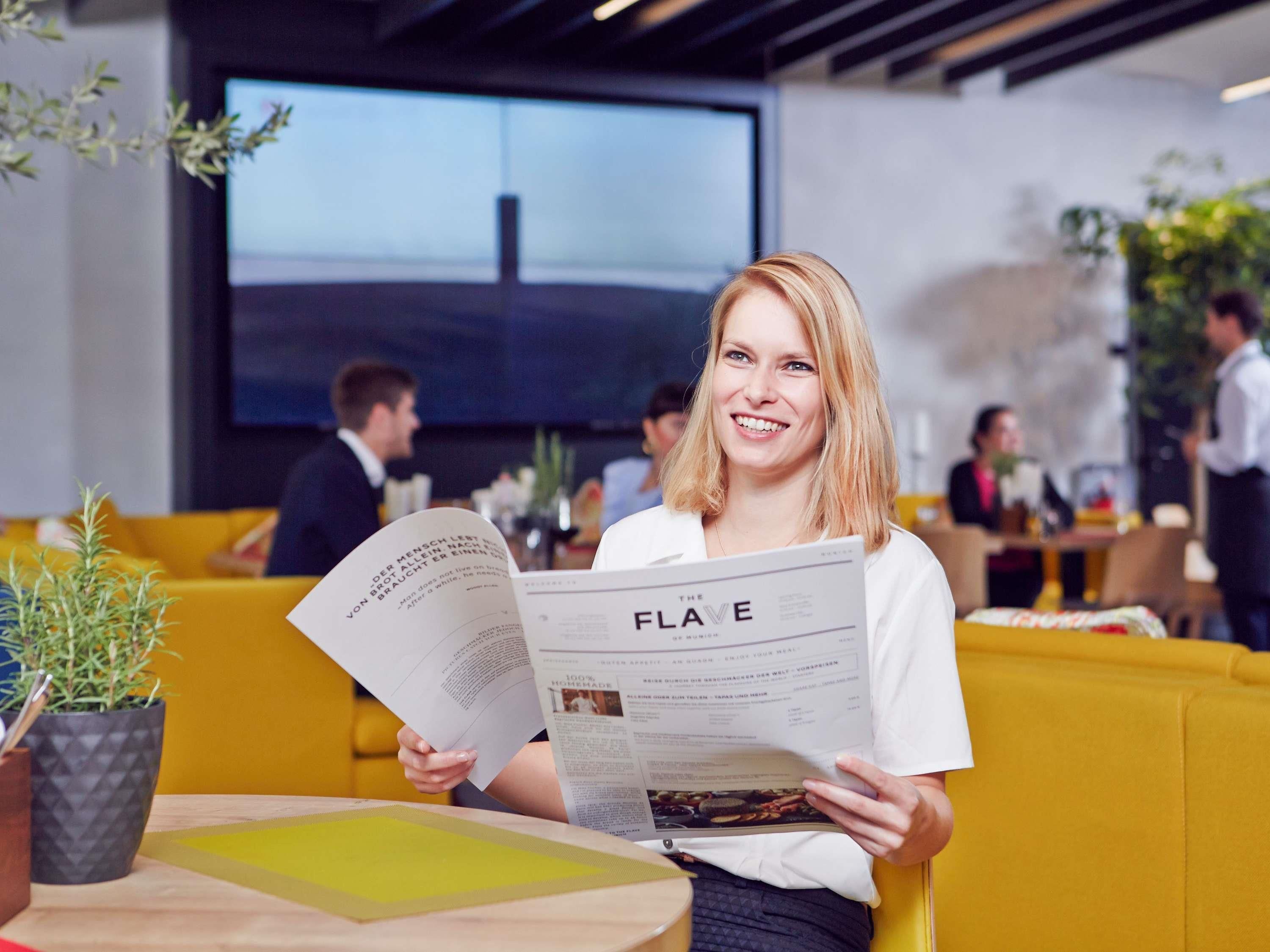 A person reading a menu in a modern, well-lit indoor space with seating and tables.