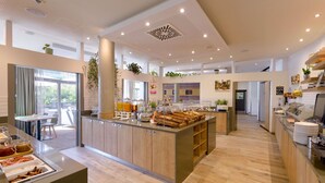 Une cuisine d’hôtel moderne dotée d’un îlot central, d’un bar pour le petit-déjeuner et de différents postes de préparation des aliments.