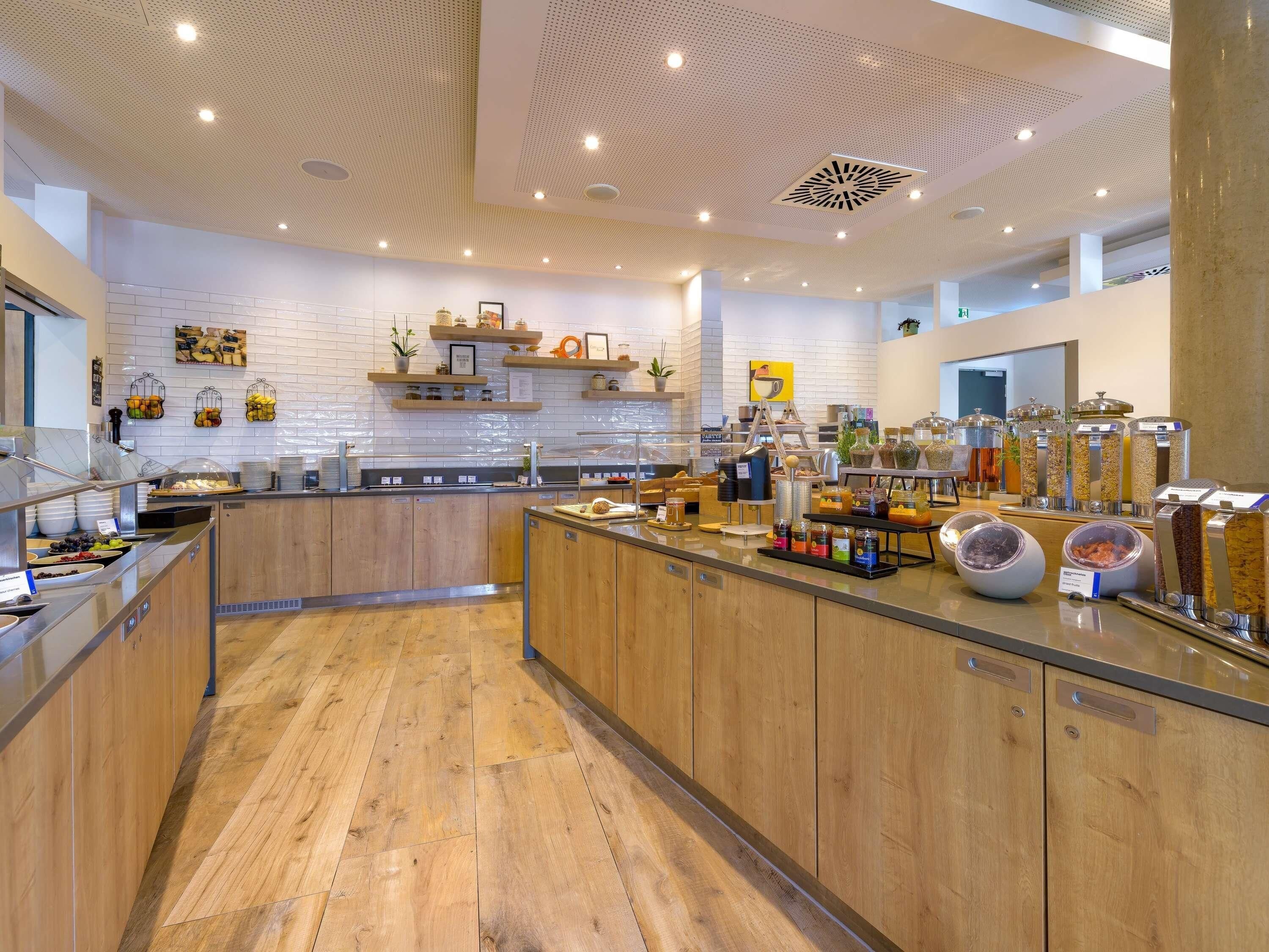 Een moderne keuken met houten kastjes, een centraal eiland en diverse voedseldispensers.