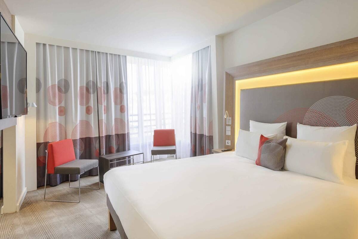 Een hotelkamer met een groot bed, een bureau, een stoel en een televisie.