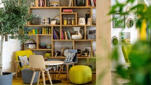 Une pièce chaleureuse avec une bibliothèque en bois, une table à manger entourée de chaises et un pouf jaune.