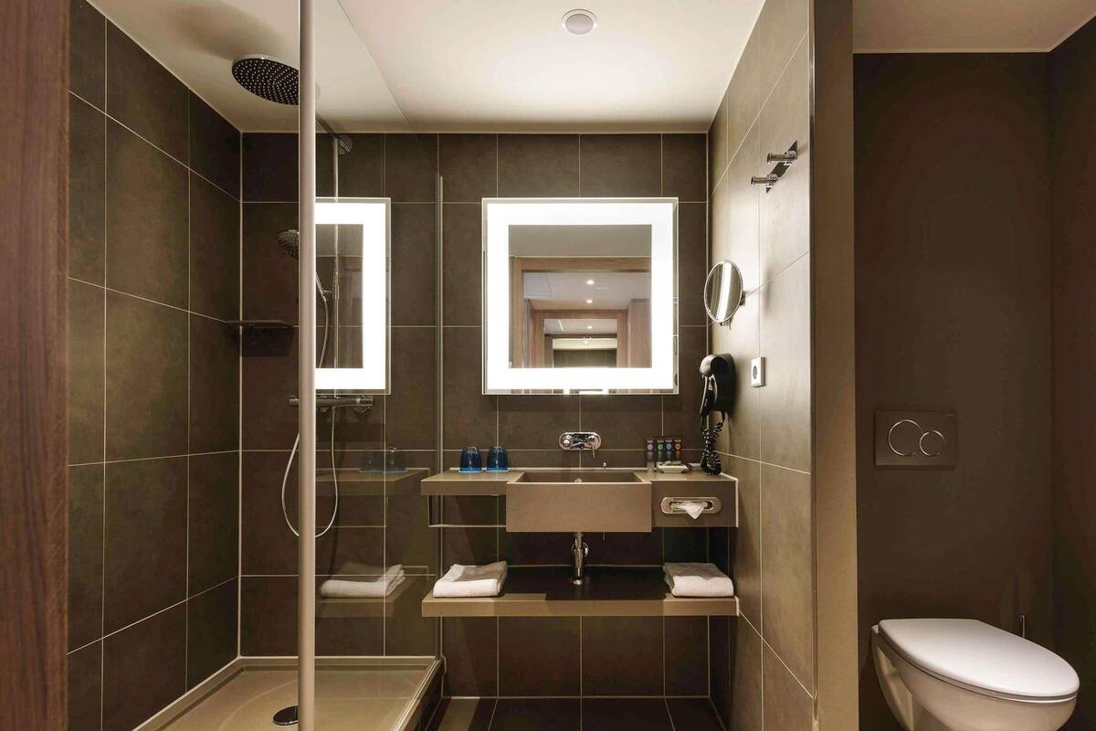 Een moderne badkamer met een douchecabine van glas, een wastafel met spiegel en een toilet.