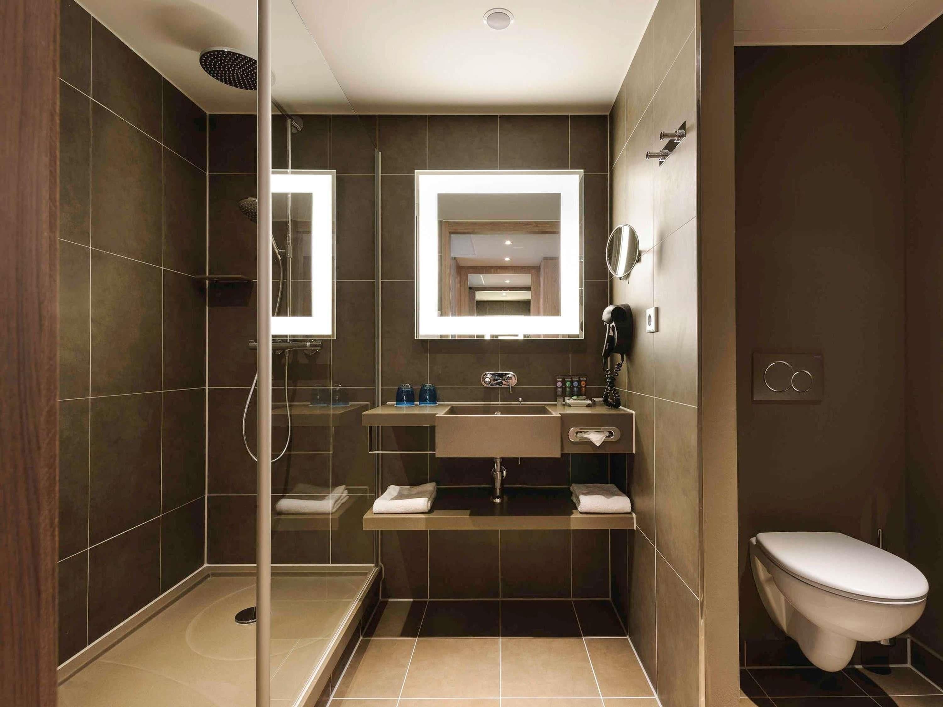 Ein modernes Badezimmer mit einer gläsernen Duschkabine, einem Waschtisch mit Spiegel und einer Toilette.