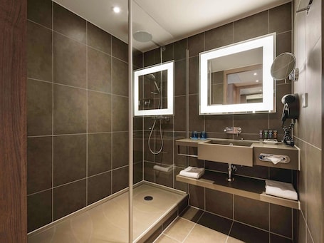 A modern bathroom with a glass-enclosed shower, a vanity with a mirror, and a towel rack.. Novotel München City Arnulfpark