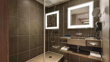 Un baño moderno con ducha de vidrio, tocador con espejo y perchero para toallas.