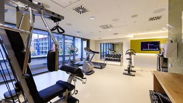 Ein modernes Fitnessstudio mit vielfältigen Trainingsgeräten, großen Fenstern und hellem Innenraum.