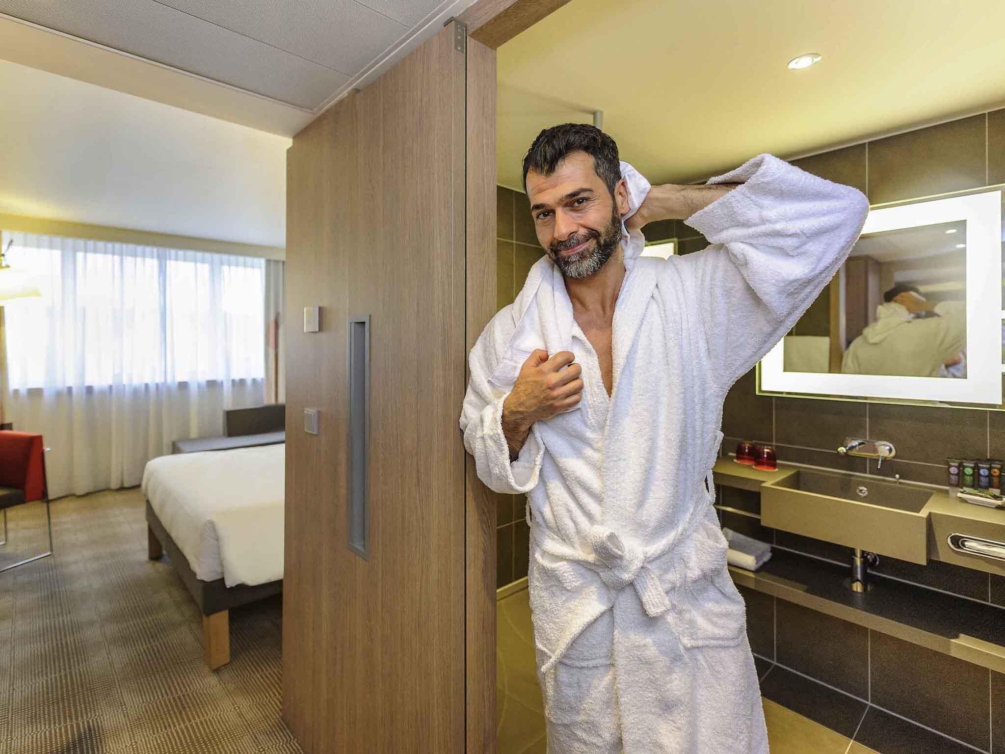 Ein Hotelzimmer mit einem Bett, einem Holzschrank, einem Badezimmer mit Spiegel und Pflegeprodukten.