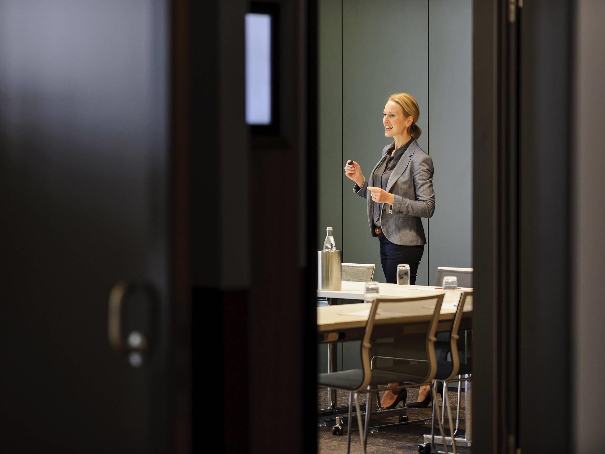 A conference room with a table, chairs, a water bottle, and a presentation screen.