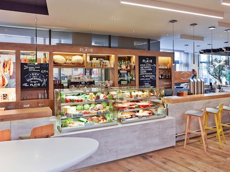 A bakery counter with a variety of breads and pastries, a coffee machine, and a selection of beverages.. Novotel München City Arnulfpark